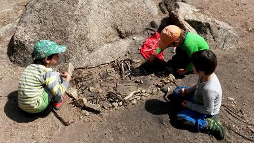 Niños jugando con ramas y piedras